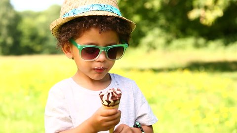 Little boy licking ice cream in a cone during summertime