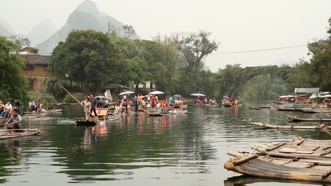 YANGSHUO, GUANGXI, CHINA - OCTOBER 21: Bamboo raft on Yulong river with ancient stone arch bridge. October 21, 2012 in Yangshuo Guilin, Guangxi, China.