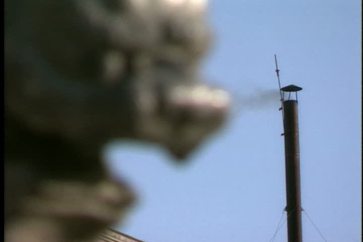 Rack focus from smokestack to an ancient carved lion statue in Beijing, China.