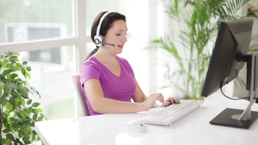 Support phone operator in headset at workplace using personal computer looking