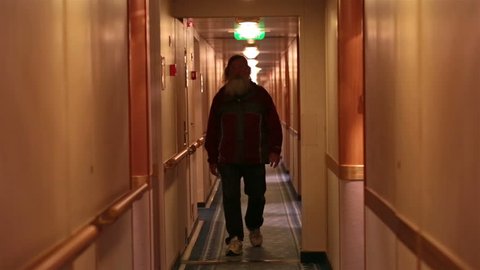 Passengers in cruise hallway. Vacation cruise to Alaska. Man walks down inside hall between cabins on luxury ship. Mature man with beard.