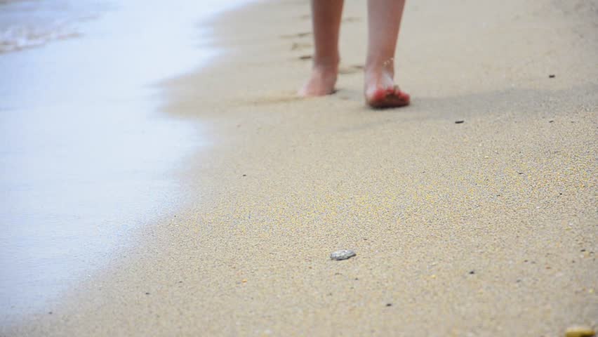 Young Woman making Footprints at the Beach, Young woman walking at the beach at