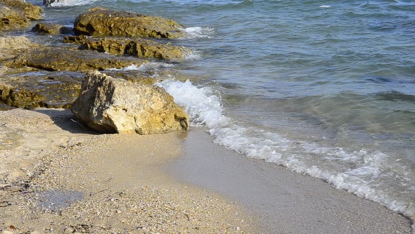 waves on sandy beach splash on the rocks