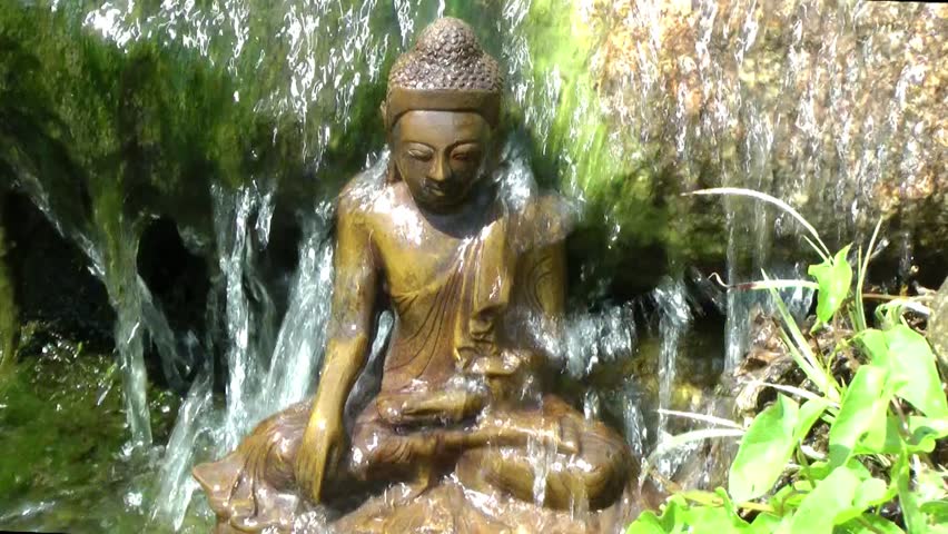 A seated statue of Buddha under waterfall