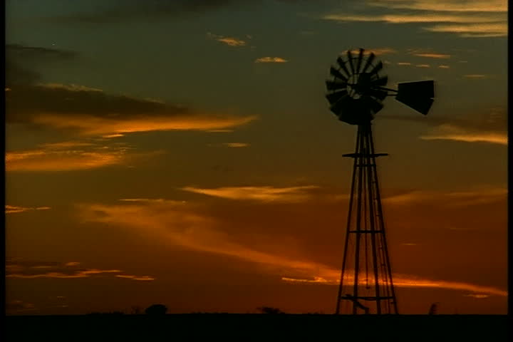 Silhouette of old farm wind pump with streaky sunset in Oklahoma Panhandle, Oklahoma.