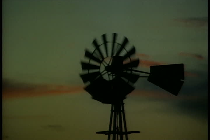 Silhouette of old farm wind pump with blades turning at sunset in Oklahoma Panhandle, Oklahoma.
