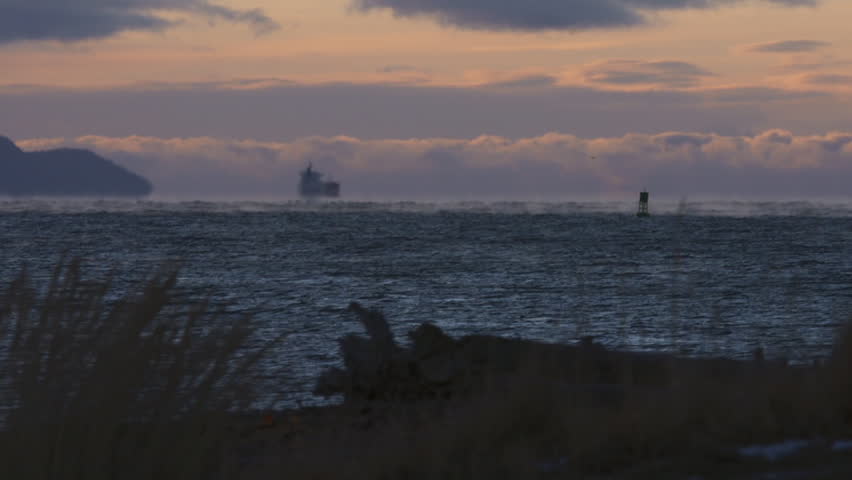 An oil tanker bobs on the horizon on a cold, windy day on Kachemak Bay in Alaska