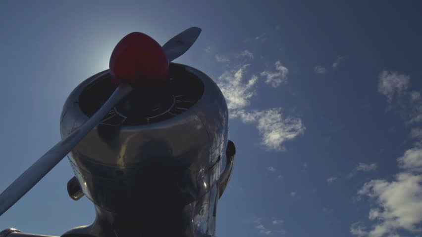 Dolly angle view of an old propeller plane, revealing a sunburst above
