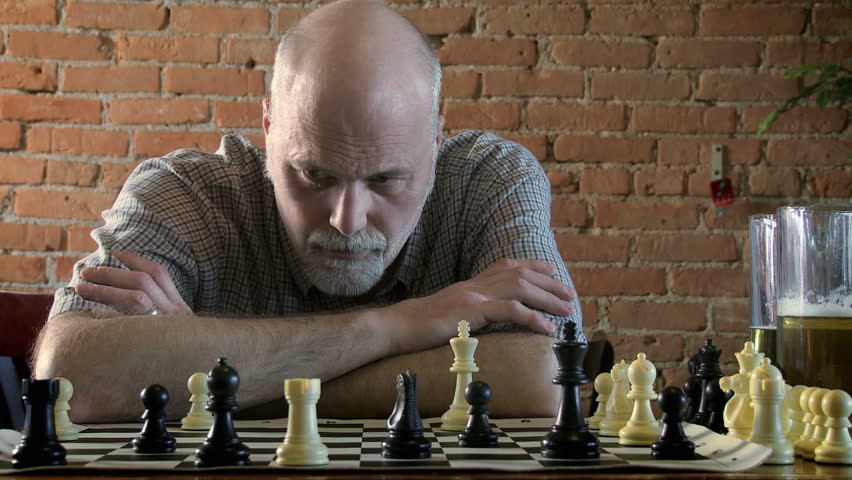 Medium shot of man playing chess in a bar.  Camera tilts during the action.