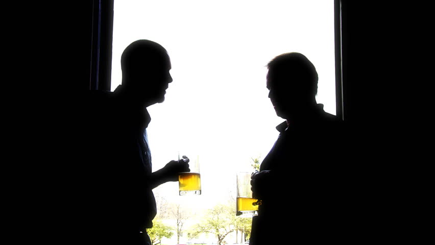 Two men silhouetted in a doorway, drinking lager.
