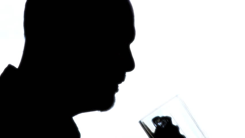 Silhouetted close up of man drinking lager beer.