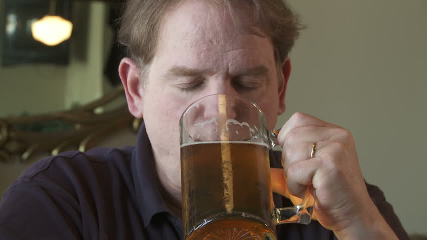 Close up of man drinking a glass of beer.