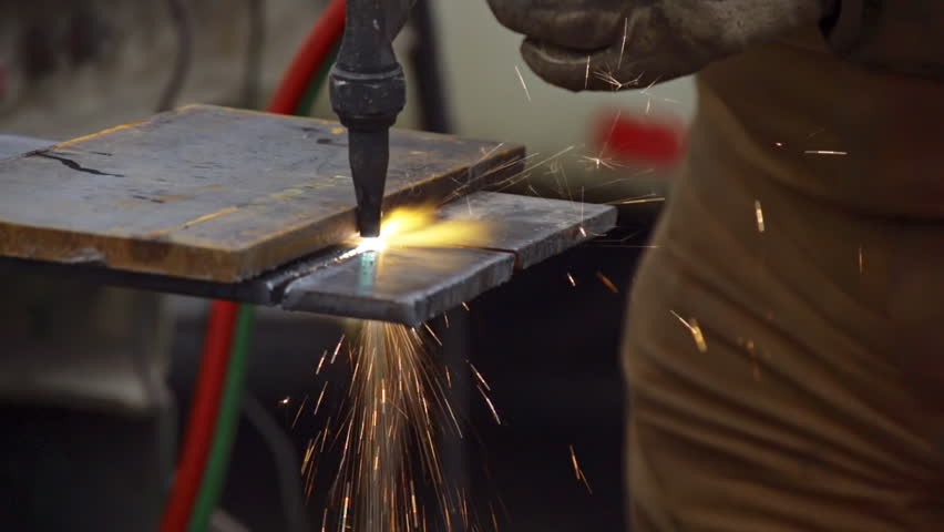 Close-up of an industrial worker cutting a steel plate with an oxy-acetylene