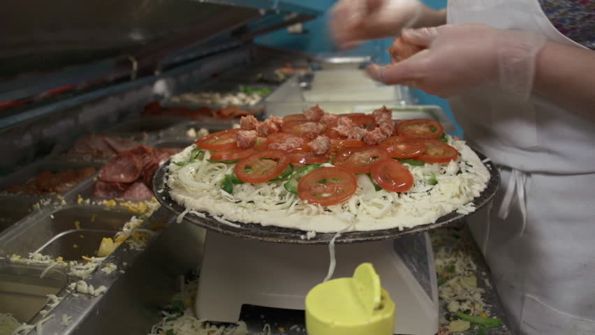 Young female chef shreds Italian sausage to make a gourmet pizza pie
