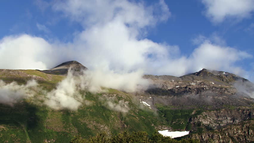 White clouds and mists grow, gather, and dissipate in this scenic mountain time