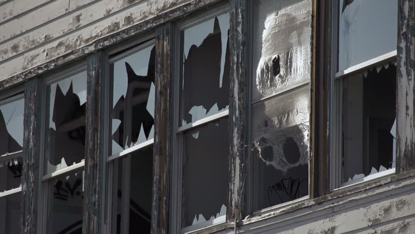 Abandoned building has broken windows ringed with shards of glass and ragged