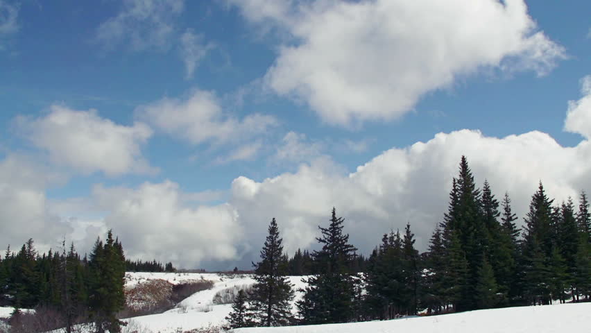Time lapse of storm clouds gathering to blot out a bright blue sky over a snowy