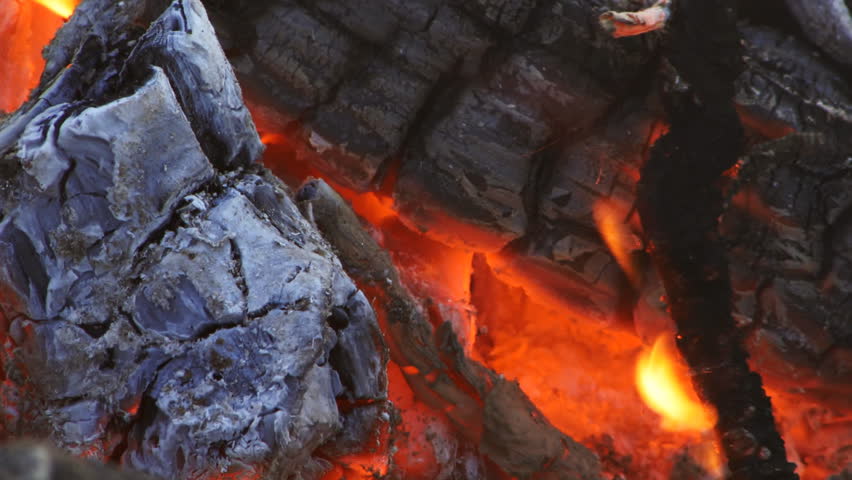Close-up of hot coals of a campfire, with heat wave distortion and smoke