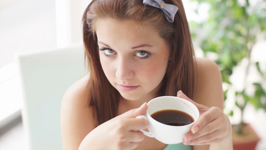 Pretty girl with cup of coffee laughing at camera

