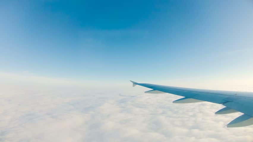 View of wing of plane, flying above the clouds, and then starting landing and
