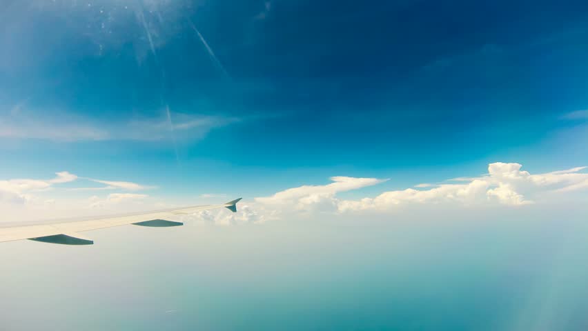 View of sky and wing of plane flying through clouds, Time Lapse 