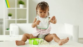 Female toddler sitting on the table and playing with cooked spaghetti