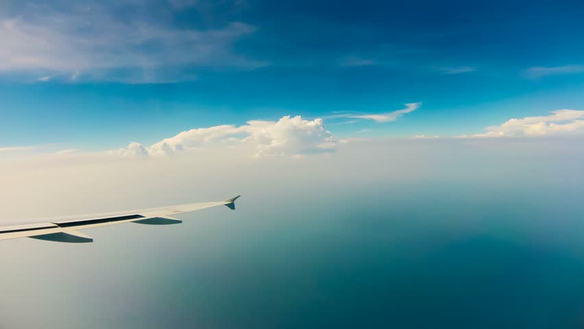 View of blue sky and wing of plane flying through clouds, Time Lapse 