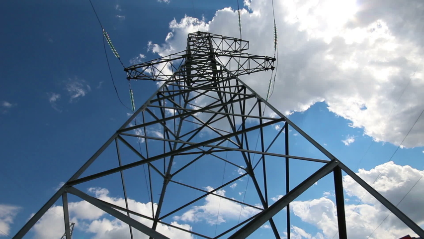 tall electric masts against sun and cloudy sky - timelapse