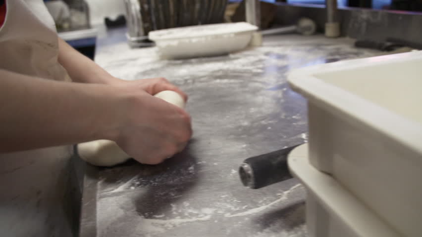 Young woman forms and rolls out pizza dough