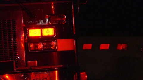 Flashing emergency lights reflect off back of a firetruck with brake lights