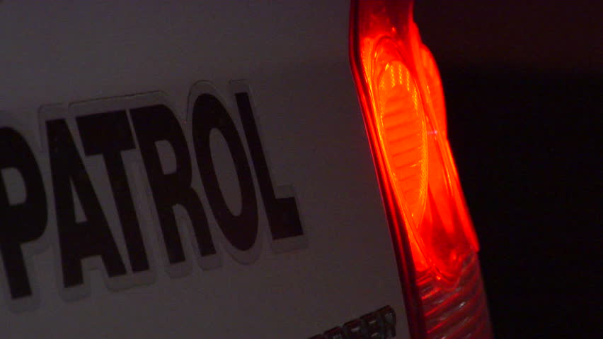 Flashing emergency sirens reflect off police cruiser tail light