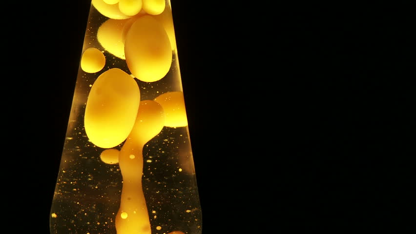 Yellow lava lamp, cropped tightly against a dark background.  Space at side for