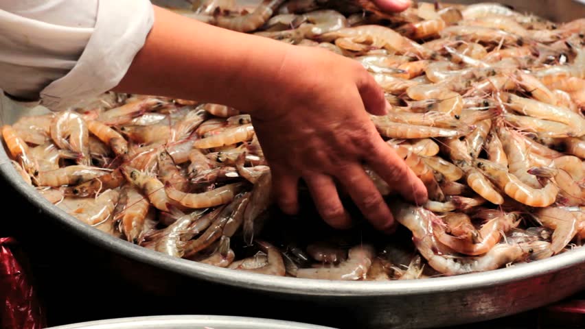 Shrimps being stirred by hand in a open air seafood market. Man moves fresh
