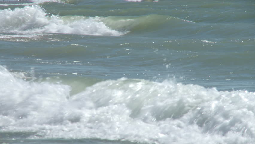 Angled view of waves breaking on a sunny day.  Looping clip with dissolve