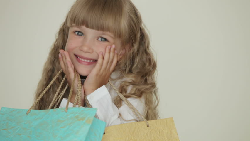 Adorable little girl holding multicolored paper bags smiling laughing and making