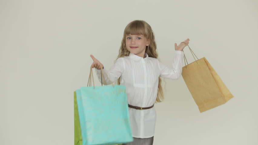 Funny little girl posing with with multicolored paper bags and smiling at