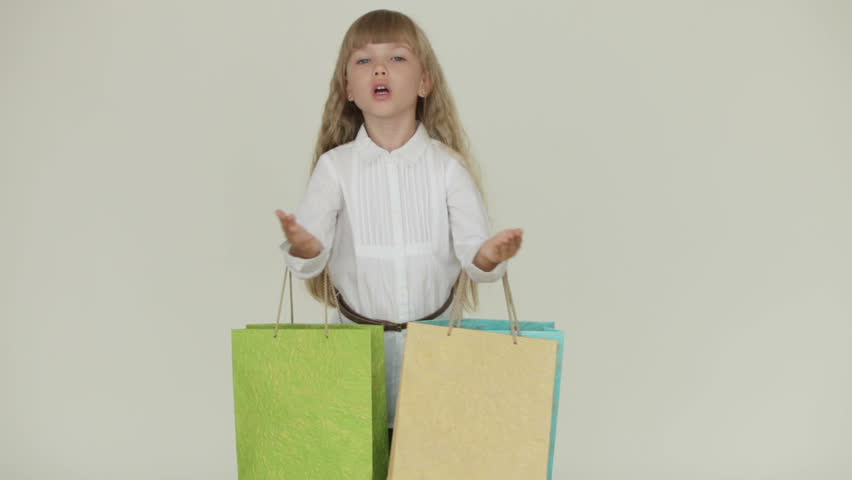Beautiful little girl holding multicolored paper bags and blowing kiss to
