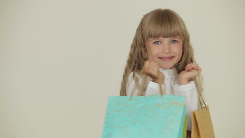 Cheerful pretty little girl posing with multicolored paper bags
