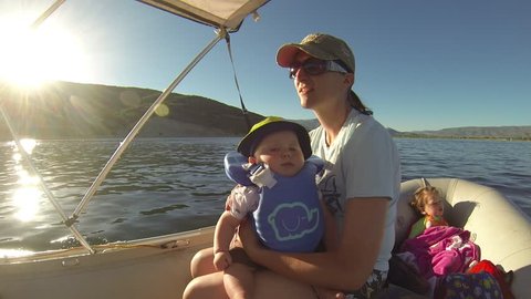 Mother and baby and daughter riding on a boat in the lake. 