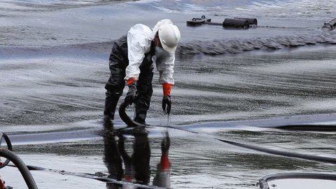 RAYONG, THAILAND - JULY 31, 2013: A worker in biohazard suit during the clean-up operation from crude oil spilled into Ao Prao Beach on July 31, 2013 in Rayong province, Thailand. 