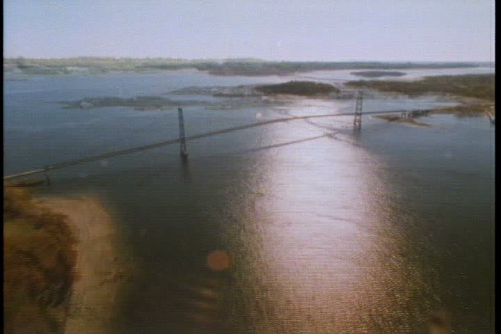 Aerial WS over river as it passes under big traffic bridge and flows out to sea in New England.