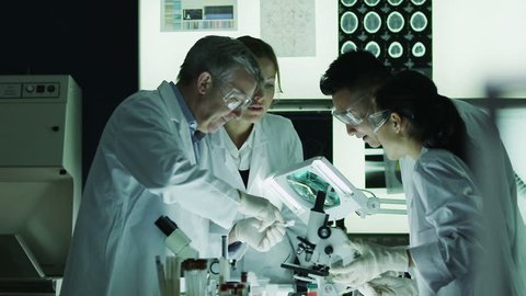 Diverse team of scientists or researchers working together in a dark laboratory, carrying out experiments and analyzing their findings.
