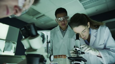 Young scientific research team analyzing samples in dark laboratory