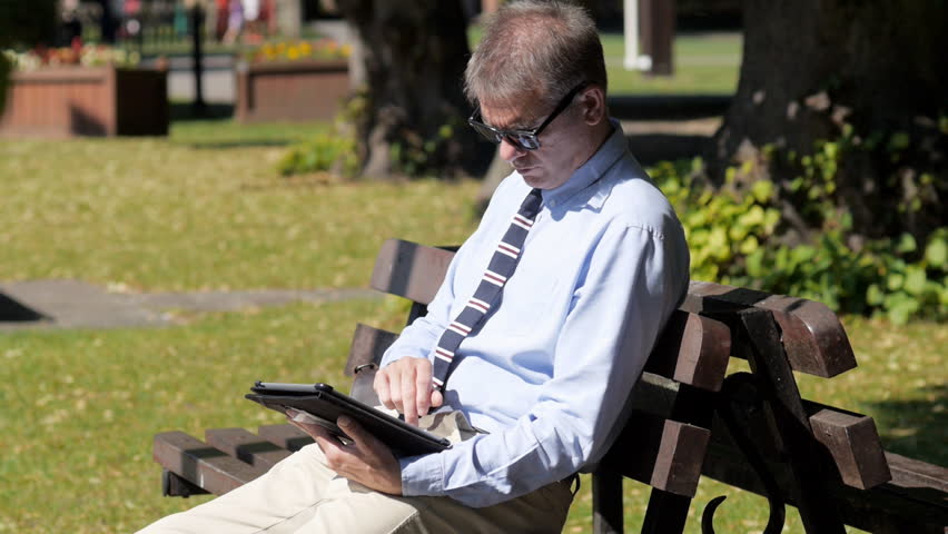 Business man with tablet pc in park