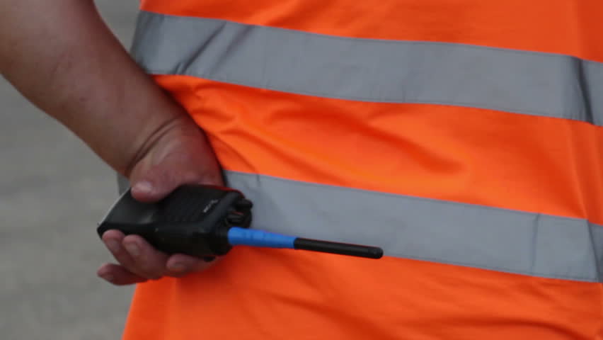 Clumsy security with walky-talky in orange uniform standing