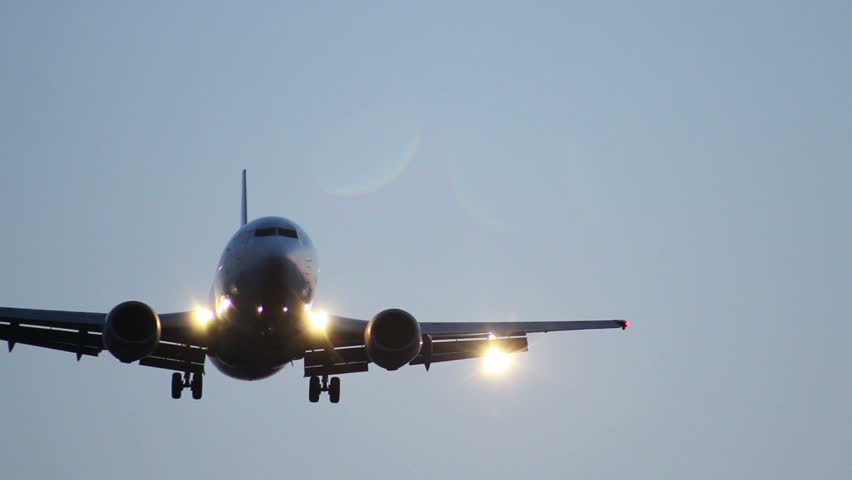 Passenger airliner with lights approaches, flies above, landing