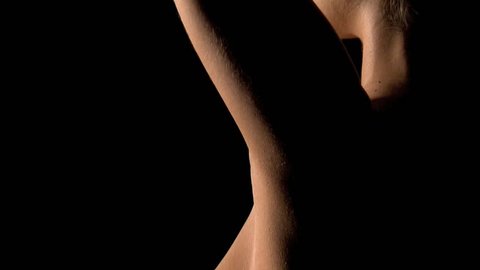 Creative and artistic, tasteful nude shot of a young woman on a black background.