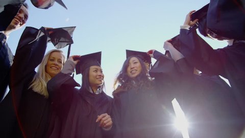 Graduation caps are tossed into the air by a happy group of friends on a bright sunny day. In slow motion. with flare.
