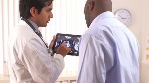 Hispanic doctor using tablet pc to share MRI with patient