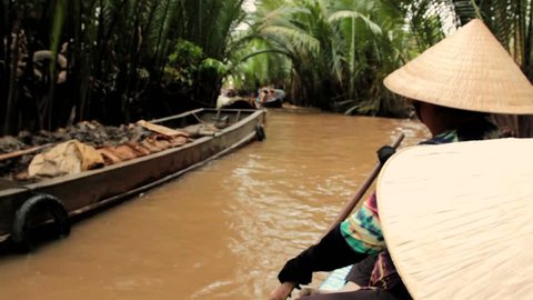 Vietnamese woman rowing a boat on a canal in Mekong delta, Vietnam